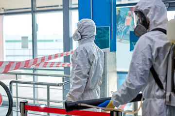 workers in hazmat suits and face mask protection while making disinfection indoors, coronavirus...