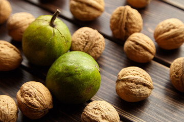 Dry and unripe walnuts with green pericarp on wooden background
