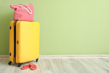Packed suitcase with beach accessories near color wall