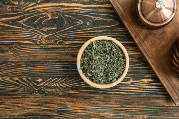Fototapeta na wymiar Bowl with dry green tea on wooden table