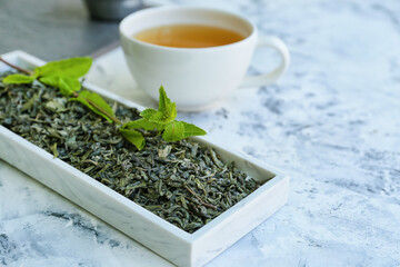 Dry leaves and cup of green tea on table
