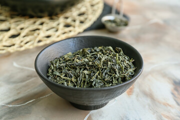 Bowl with dry green tea on table