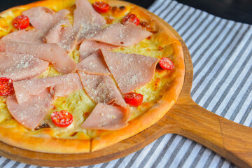 Pizza with bacon, salami and vegetables. Ham and tomatoes pizza with melted cheese.