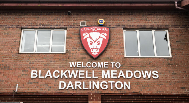 Sign on the outside wall of the Blackwell Meadows rugby and football ground in Darlington whowing shield logo of Darlington Rugby Footablee Club