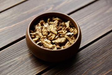 Walnut seeds in bowl on wooden background