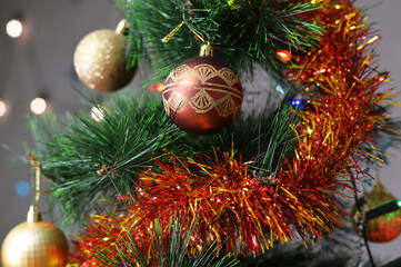 Photo of branches of a New Year tree with decorations on a background of a gray wall. New Year concept.