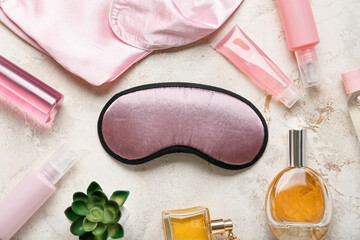 Sleep mask, pajamas and cosmetics on color background