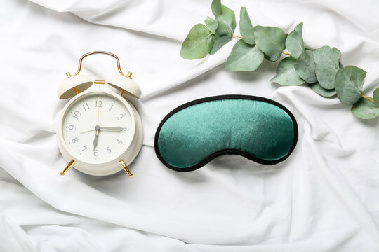 Sleep mask and alarm clock on light background