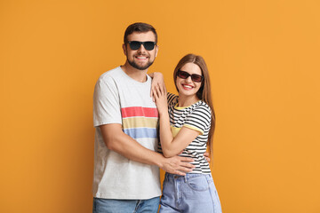 Fototapeta premium Young couple with stylish sunglasses on color background
