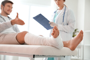 Young man with broken leg visiting doctor in clinic