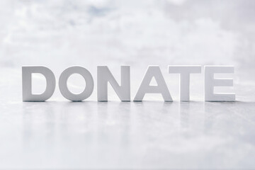 Word DONATE made with cement letters on grey marble background. Copy space. Biblical, spiritual or...