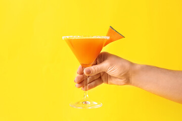 Female hand with glass of tasty pumpkin pie martini on color background