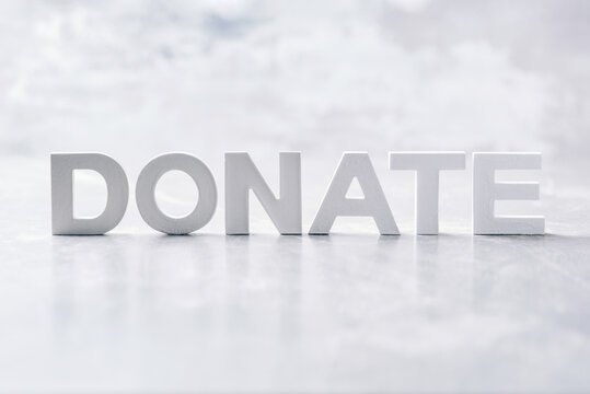 Word DONATE made with cement letters on grey marble background. Copy space. Biblical, spiritual or christian reminder