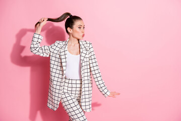 Photo of attractive person kiss look empty space arm hold hair tail white plaid outfit isolated on pink color background