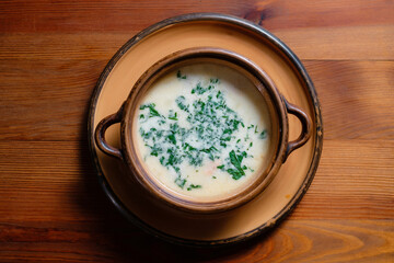 Soup with herbs in a clay plate.