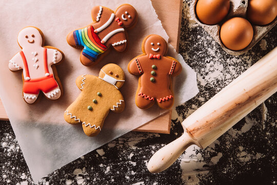 Christmas gay cookies. Festive pastry collection. Sexual identity. Social diversity. Gingerbread men colorful decorated icing ornament on floured kitchen black desk.