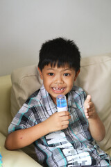 AnAsian youngboy use an alcohol nano mist sprayer for hand cleaning.