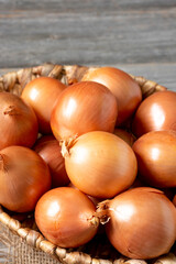 Onions in the basket. Onions in a wicker basket on a wooden table. Onion plant closeup