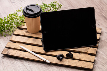 飲み物と黒いイヤホンとタブレット端末が木製の机に置いてある　tablet...