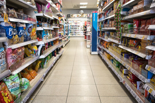 Grocery store aisle showing crisps, biscuits and snacks.  Nobody in shot