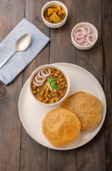 Spicy chick peas curry or Chana Masala or choley with fried puri garnished with sliced onion and green coriander leaf