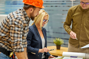 architects and engineers working with blueprints and architectural plan, female director talk with...
