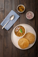 Spicy chick peas curry or Chana Masala or choley with fried puri garnished with sliced onion and green coriander leaf