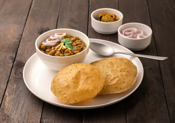 Spicy chick peas curry or Chana Masala or choley with fried puri garnished with sliced onion and...