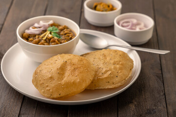 Spicy chick peas curry or Chana Masala or choley with fried puri garnished with sliced onion and green coriander leaf