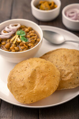 Spicy chick peas curry or Chana Masala or choley with fried puri garnished with sliced onion and green coriander leaf