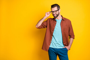 Obraz premium Photo portrait of young bearded businessman touching glasses smiling looking empty space isolated on bright yellow color background