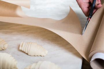 Baking paper. Bake a croissant. Scissors cut the paper.