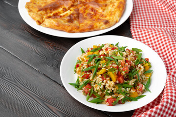 Georgian Tabbouleh salad with bulgur and vegetables on black wooden table
