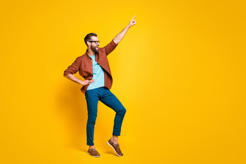Full size photo of cheerful happy handsome young guy dance point finger hold hand waist empty space...