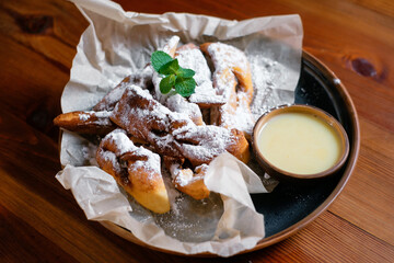 Fresh baked goods with powdered sugar garnished with a mint leaf side view.