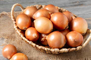 Onions in the basket. Onions in a wicker basket on a wooden table. Onion plant closeup