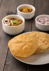 Spicy chick peas curry or Chana Masala or choley with fried puri garnished with sliced onion and green coriander leaf