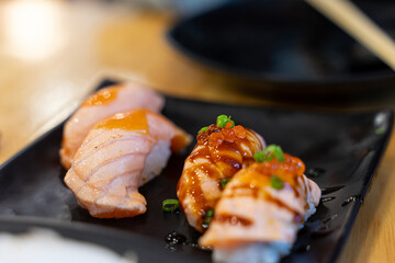 Salmon sushi, raw and grilled In the black plate