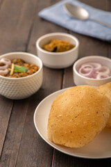 Spicy chick peas curry or Chana Masala or choley with fried puri garnished with sliced onion and green coriander leaf
