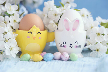 Easter background. Happy Easter holiday concept with cute colorful eggs, bunny, chicks and flowers on blue table background. Greeting card