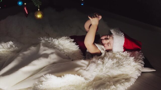 a child in red clothes is sitting waiting for the new year. the concept of celebrating Christmas at midnight. holiday costume