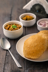 Spicy chick peas curry or Chana Masala or choley with fried puri garnished with sliced onion and green coriander leaf