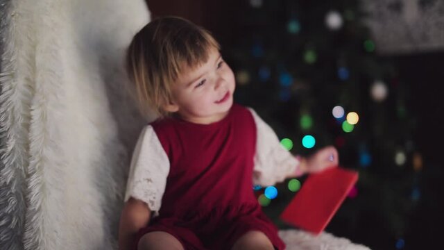 a child in red clothes is sitting waiting for the new year. the concept of celebrating Christmas at midnight. holiday costume. a girl writes a letter to Santa Claus. wish list