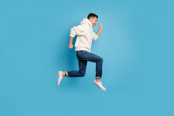 Fototapeta na wymiar Full size profile sde photo of young happy cheerful positive smiling man jump run isolated on blue color background