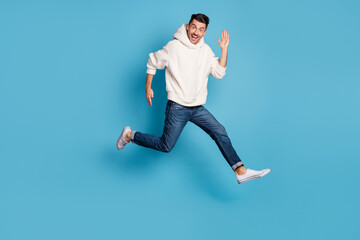 Fototapeta premium Full size photo of young excited positive happy smiling man jumping running say hi isolated on blue color background