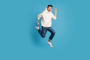 Fototapeta na wymiar Full size photo of young cheerful positive good mood man smiling jump run say hello isolated on blue color background