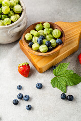 Composition with summer berries on wooden chopping, wooden bowl