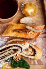 Poppy strudel and tea in a paper cup. Homemade cake with natural ingredients. Rustic wooden background. Top view. Flatlay.