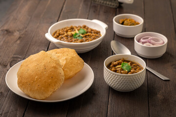 Spicy chick peas curry or Chana Masala or choley with fried puri garnished with sliced onion and green coriander leaf