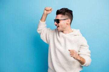 Photo portrait of cheerful man with stubble dancing isolated on pastel blue colored background